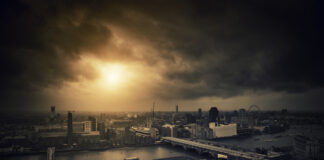Aerial view of a city skyline at sunset with a river and dramatic clouds