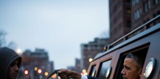 A person handing a bag to someone in a vehicle at night