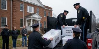 Police officers loading official ballot boxes into a truck outside a municipal building