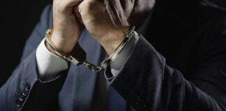 Man in suit wearing handcuffs.