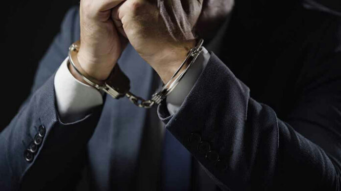 2175831991 Man in suit wearing handcuffs.
