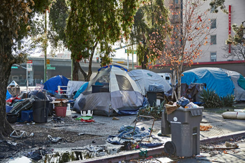 shutterstock1542195449-2jpg Homeless encampment with tents and trash in urban area.