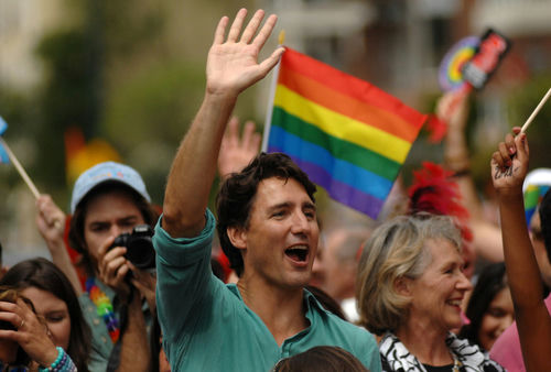 shutterstock461546152jpg Man waving in a crowd with a rainbow flag in the background