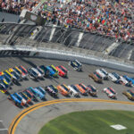 NASCAR Legend DIES – Mystery Illness STRIKES! NASCAR race at Daytona Speedway with cheering spectators.