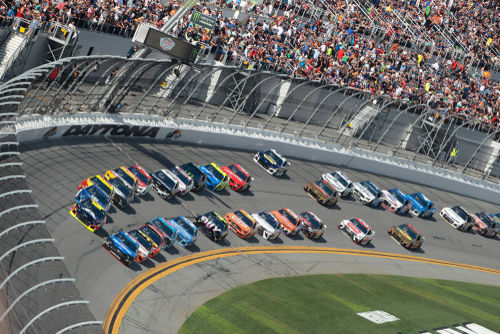 shutterstock_1316709245-1 NASCAR race at Daytona Speedway with cheering spectators.