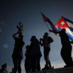 Silhouetted crowd waving Cuban flags at dusk