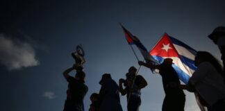 Silhouetted crowd waving Cuban flags at dusk