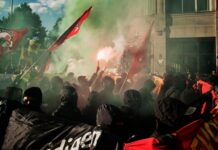 Billionaire BUSTED Playing Working-Class Hero — Backfires! Crowd of protesters with smoke flares and flags during a demonstration
