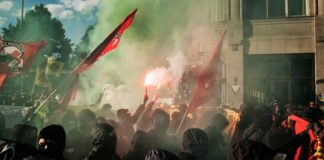 Crowd of protesters with smoke flares and flags during a demonstration