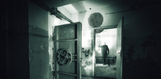 A dark, abandoned room with a mysterious figure in the background