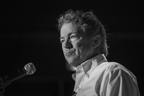 shutterstock_527871586.jpg A man with curly hair speaking into a microphone in black and white