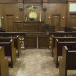 Viral AXE CLIP Backfires in Court Empty courtroom with wooden benches and judges bench.