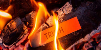 Truth card burning in flames on charred wood.
