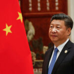 A man in a suit beside the Chinese flag.