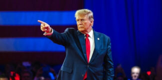 Man in suit pointing on a stage.