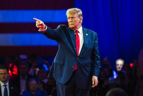 shutterstock2430065795-1jpg Man in suit pointing on a stage.