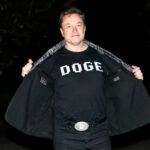 Defamation Showdown: Musk Goes Nuclear Man opening his coat to show a graphic T-shirt at night