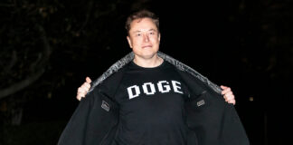Man opening his coat to show a graphic T-shirt at night