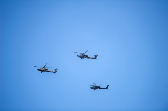Vilnius,-,Mar,22:,Us,Army,Apache,Ah-64,Helicopters,During A drone flying over a vast agricultural landscape