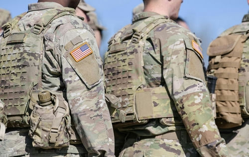 shutterstock_2145891607-1 Soldiers in camouflage uniforms with American flag patches.