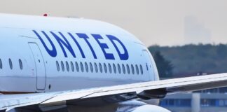 Flight attendant closing an overhead bin on airplane.