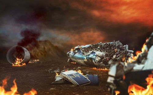 shutterstock_498828889 Burning airplane wreckage scattered across a desolate landscape.