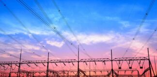 Electrical substation and power lines at sunset with vivid sky and reflections