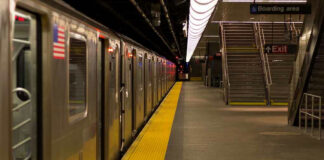 Subway station platform with train and exit stairs.