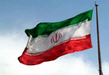 Iranian flag flying against a clear sky.