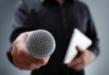 Person holding a microphone and a tablet.