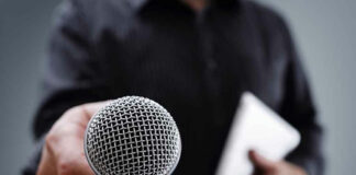 Person holding a microphone and a tablet.