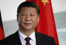 Man in suit standing before Chinese flag.