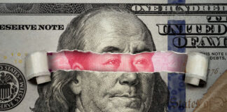 Torn dollar revealing Chinese yuan behind Benjamin Franklins eyes.