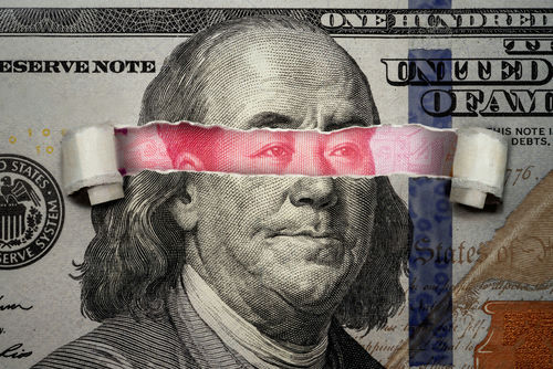 shutterstock1920302249-1jpg Torn dollar revealing Chinese yuan behind Benjamin Franklins eyes.