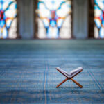 Outrage Boils Over Mosque Loudspeaker Ban Quran on stand inside mosque with stained glass windows.