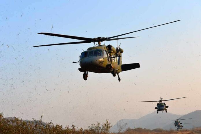 shutterstock_1159121266-3 Military helicopters flying low over a dry landscape
