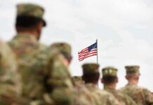 CENTCOM Moves: Ships Redirected U.S. flag flying above a formation of soldiers in uniform