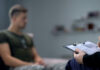 Therapist taking notes while talking with a young man.