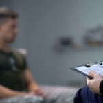 Debt Forgiveness Trap Targets Troops Therapist taking notes while talking with a young man.