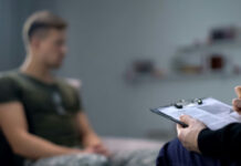 Debt Forgiveness Trap Targets Troops Therapist taking notes while talking with a young man.
