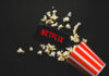 Woke Disclaimer Hijacks Hollywood Icon Spilled popcorn, phone displaying Netflix logo, striped popcorn container.