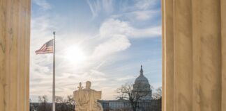 White building with columns under a blue sky.