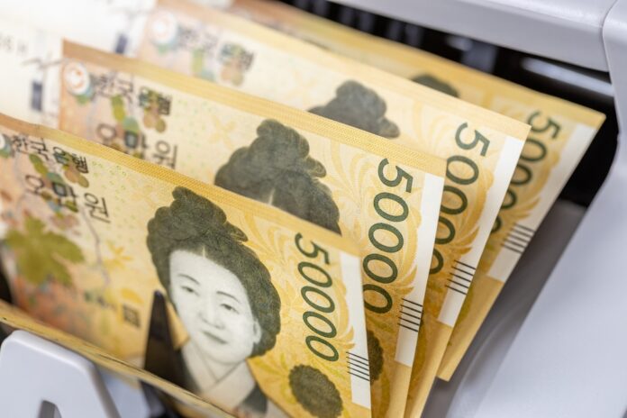 South,Korean,Money,,Korean,Won,,Banknotes,In,A,Counter,,Financial Person viewing stock market data on multiple screens.