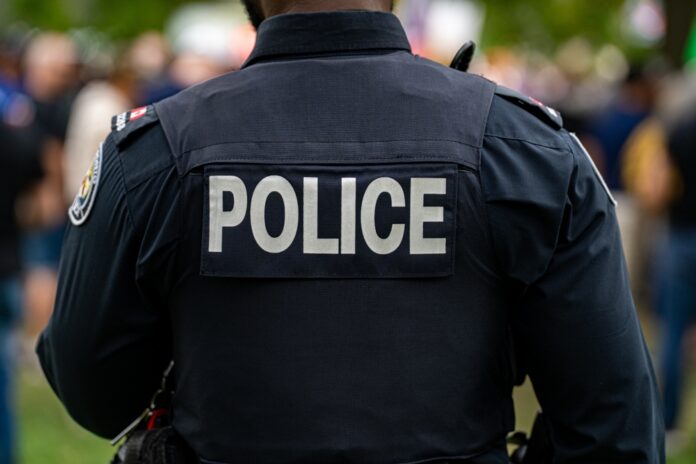 Back,View,Of,Police,Uniform,With,Label. Back view of a police officer in uniform at a public event