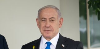 Man in suit speaking at a meeting table.