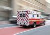 Ambulance driving on street with blurred background.