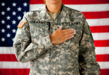 Soldier saluting in front of an American flag.