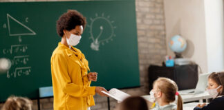 Teacher interacting with masked students in classroom.