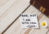 Note with Bible and daisy on wooden table.