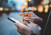 Person using smartphone in a lit street.